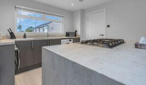 A modern kitchen with a large island, built-in appliances, and a window providing natural light. - West Lothian 5 Beds + car space (Whitburn)
