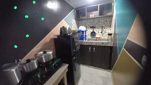 Een kleine keuken met een fornuis, gootsteen en kastjes.