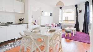 A modern kitchen with white cabinets, a dining table set for four, and a purple rug. - Harbor View Hideaway (Isigny-sur-Mer)