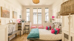 Een slaapkamer met een bed, een bureau, een stoel en een raam.