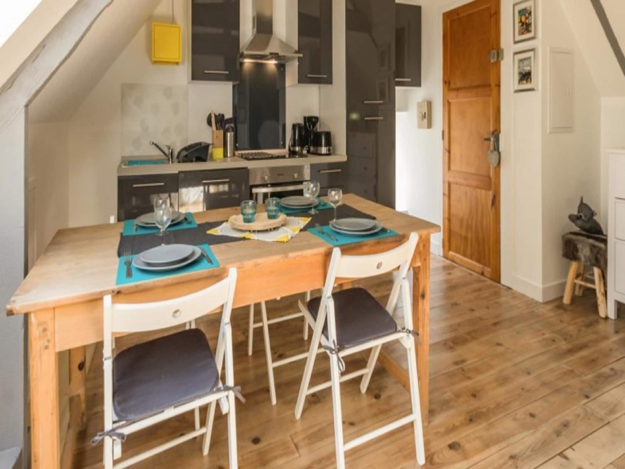 A cozy kitchen with a wooden table set for four, equipped with modern appliances and a large window.