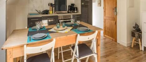 A cozy kitchen with a wooden table set for four, equipped with modern appliances and a large window.