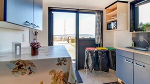 A modern kitchen with a dining area, a view through the open door, and a small outdoor seating area. - Holiday Home with Garden (Lierneux)