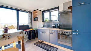A modern kitchen with a large window, a stove, and a refrigerator. - Holiday Home with Garden (Lierneux)