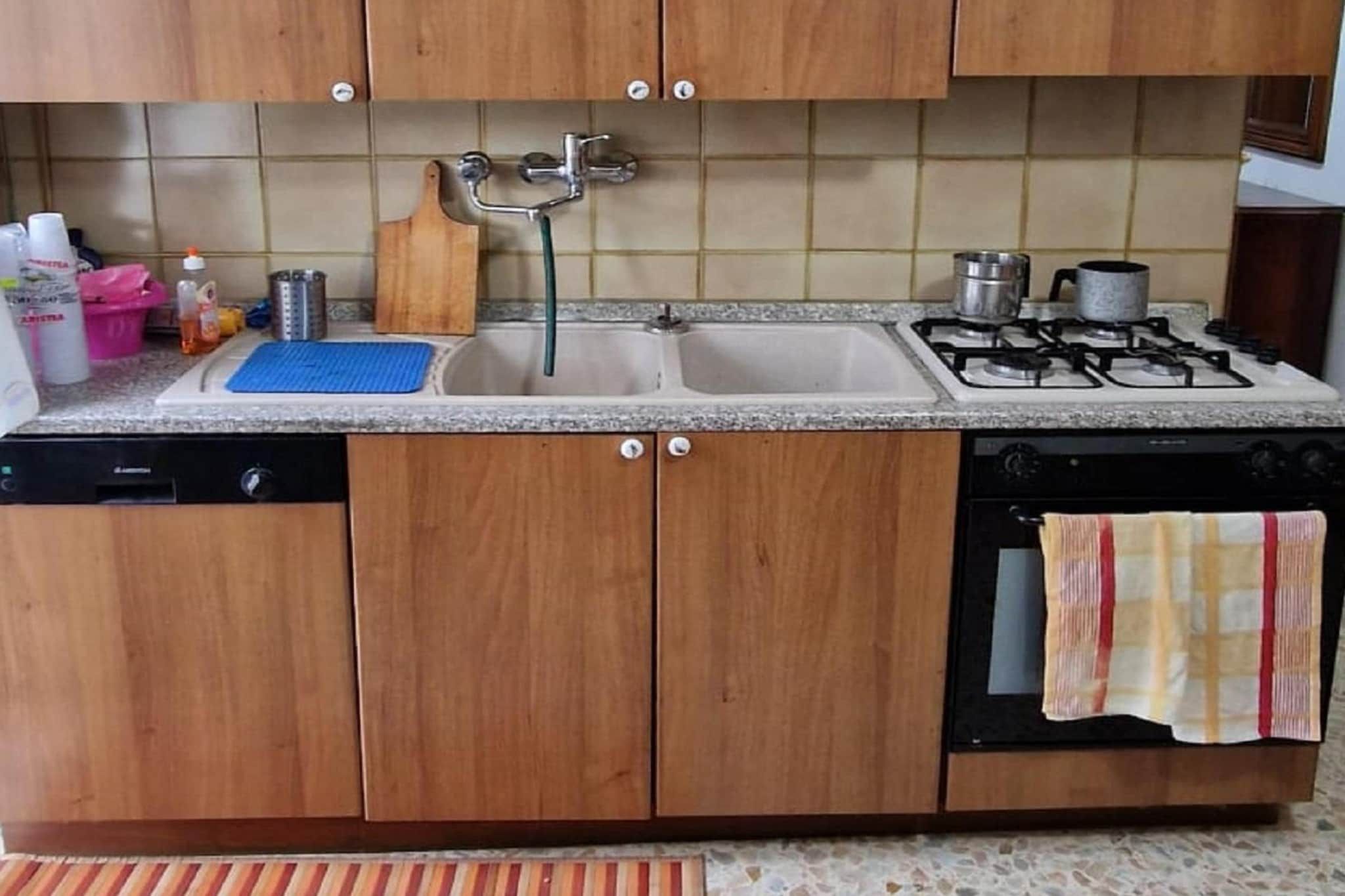 A kitchen with wooden cabinets, a double sink, a gas stove, and a dishwasher.