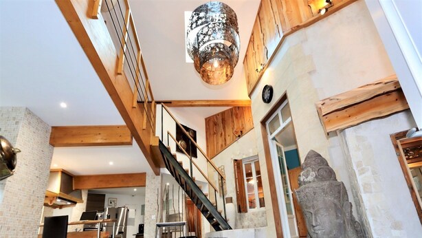 Un interior amplio con una escalera, una estatua de Buda de piedra y una zona de cocina moderna.