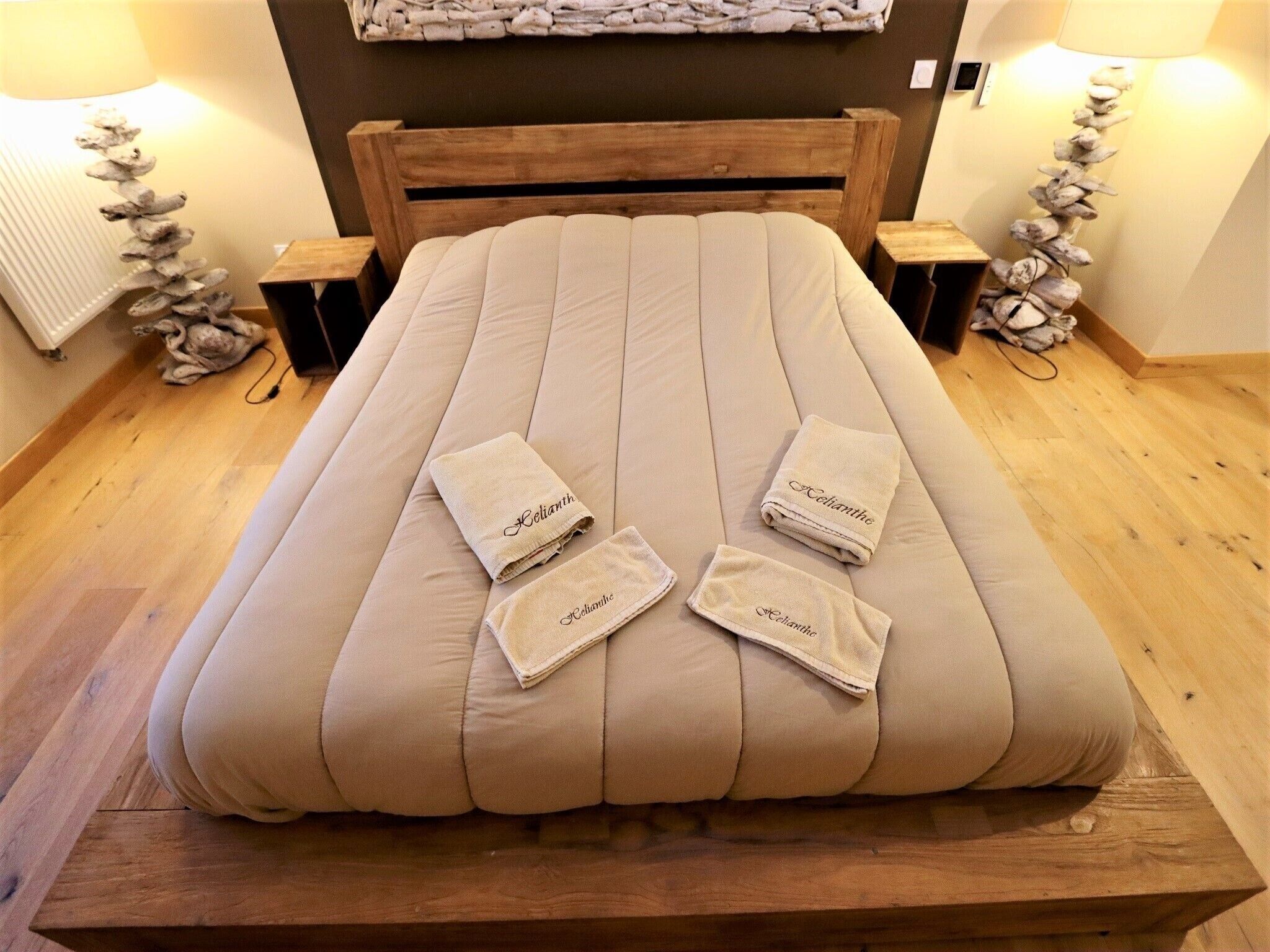 A neatly made bed with a wooden headboard, two bedside tables, and two wall-mounted lamps.