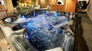 Un jacuzzi con cubierta de madera y una pequeña estructura de madera con chimenea.