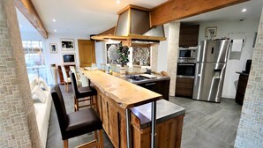 Una cocina moderna con barra de madera, electrodomésticos de acero inoxidable y salpicadero de piedra.