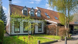 Ein traditionelles Haus mit Ziegeldach, zahlreichen Fenstern und einem Garten.