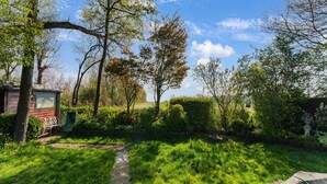 Eine rustikale Holzhütte mit einer Bank und einem Weg, der darauf führt, umgeben von üppigem Grün und Bäumen.