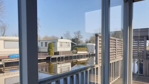 Vista de una masa de agua con un muelle de madera y una hilera de casas móviles al fondo.