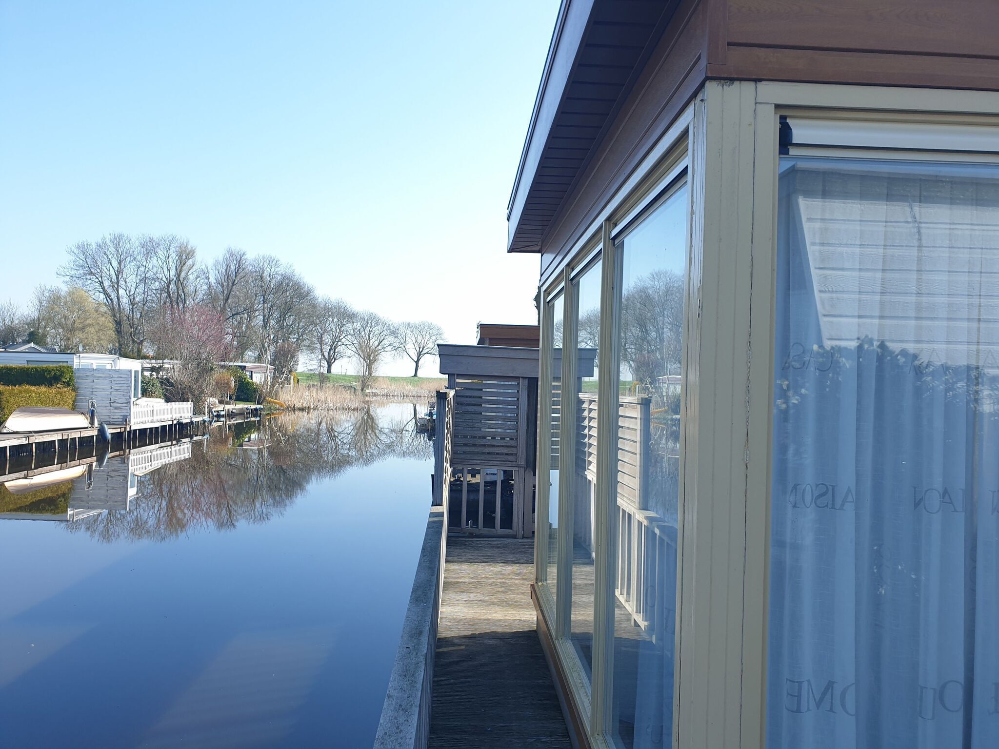 A waterfront property with a dock, a covered walkway, and a large window overlooking a calm body of water.