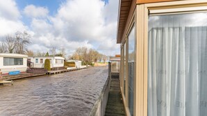 Vista junto a un canal con una hilera de casas móviles y un edificio de madera con puerta de cristal.