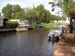A calm waterway with a wooden dock, a small boat, and a floating structure with a covered area. - Snug Holiday Home in Bantega with Own Harbour, Boathouse (Bantega)