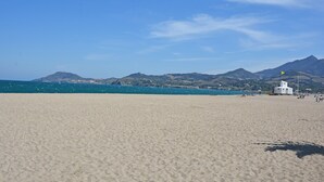 A beach with a white building, clear blue sky, and distant mountains. - Tranquil Villa with Pool (Lézignan-Corbières)
