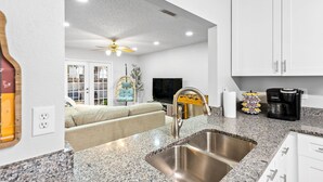 A kitchen with granite countertops, stainless steel sinks, and white cabinets.