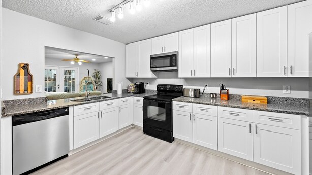 A modern kitchen with white cabinets, a black stove, and a microwave.