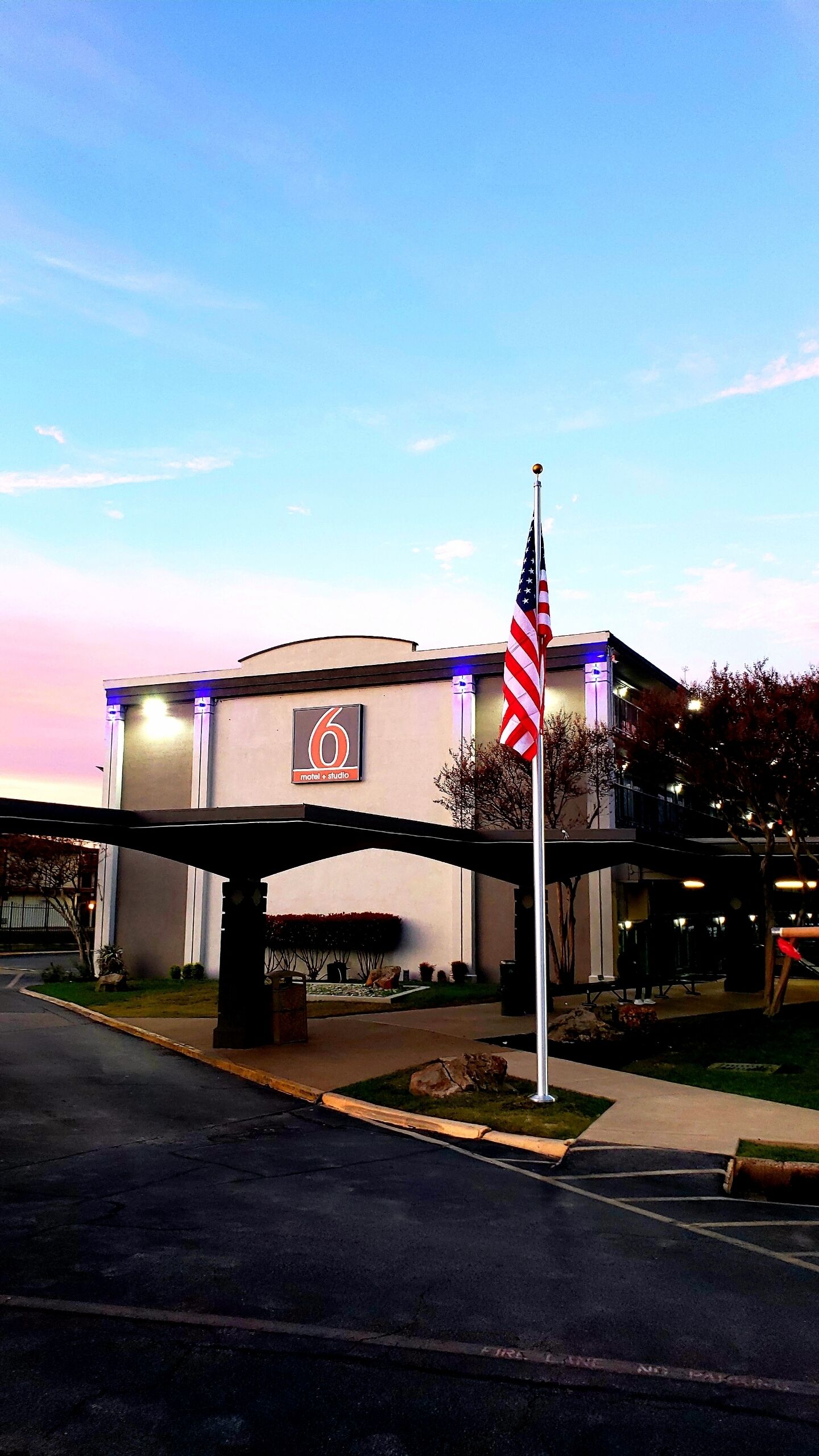 Un edificio con un letrero '6', probablemente un motel o estudio, con una bandera estadounidense al frente.