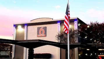 Un edificio con un letrero '6', probablemente un motel o estudio, con una bandera estadounidense al frente.