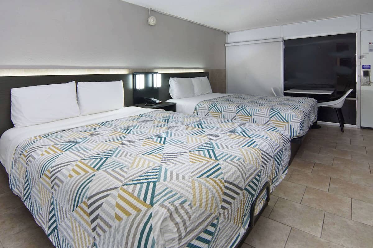 A hotel room with a large bed, a desk, and a chair.