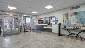 A reception area with a glass door entrance, a counter with a computer, and informational posters on the wall. - Studio 6 Mesquite, Tx – Town East (Mesquite)