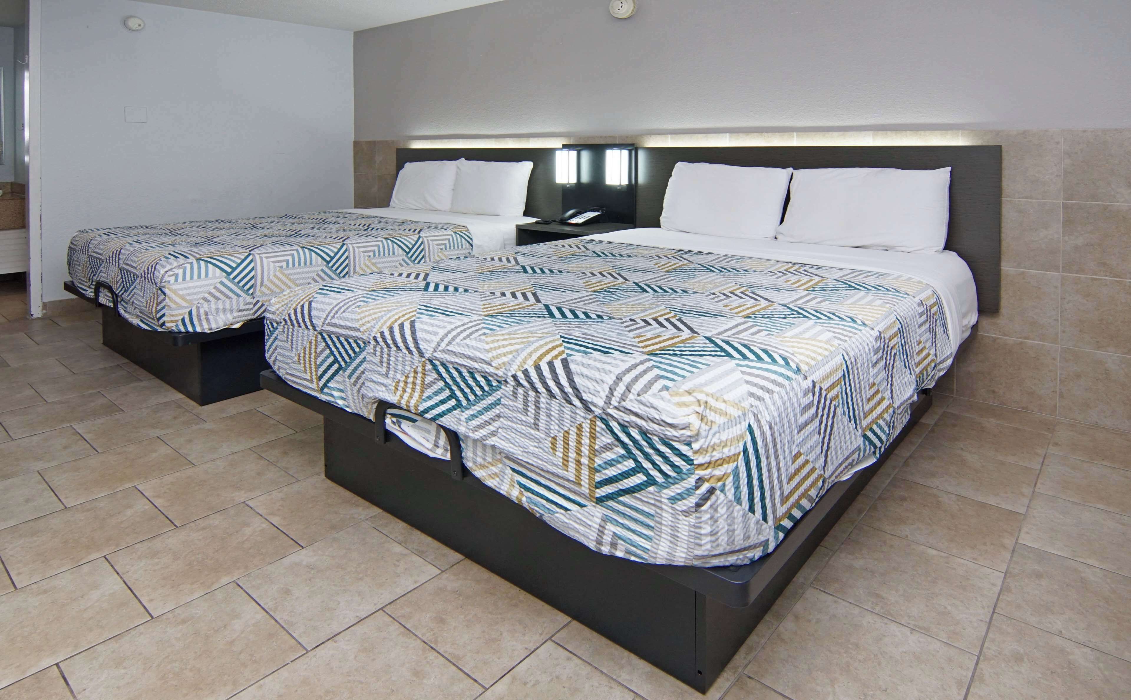 Habitación de hotel con dos camas, cada una con una colcha estampada y una mesita de noche con teléfono.