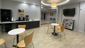 A modern cafe with a counter, seating area, and a TV mounted on the wall.
