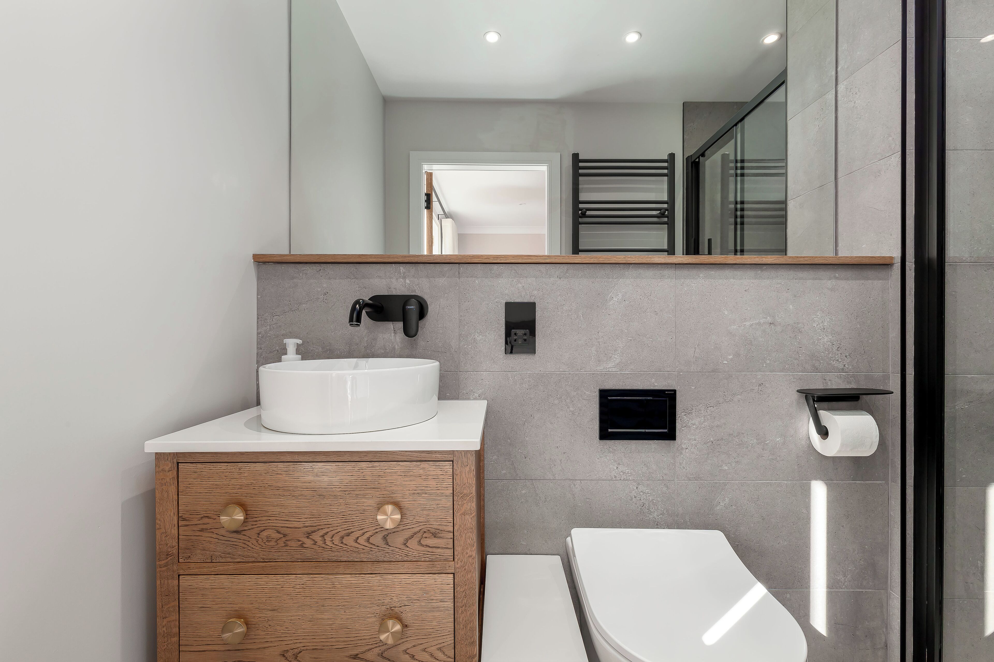Une salle de bain moderne avec un lavabo blanc, un meuble en bois et des toilettes.