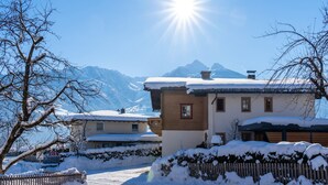 Un pueblo cubierto de nieve con edificios tradicionales y una vista despejada de montañas nevadas al fondo.