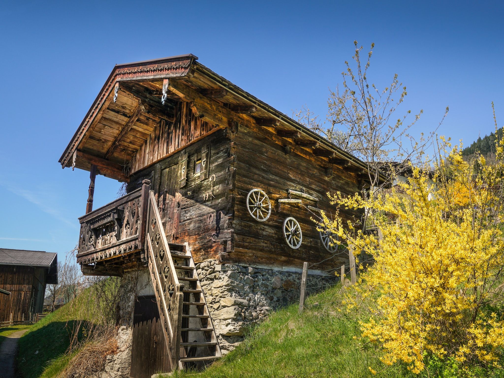 Un bâtiment rustique en bois, doté d’un balcon, de fondations en pierre et d’un escalier en bois.