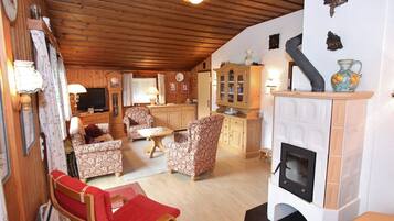 Un salon chaleureux avec des meubles en bois, une cheminée et un coin cuisine.
