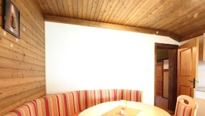 A cozy room with a wooden ceiling, a striped bench, a round table, and a door leading to another room. - Chalet in Austria near Ski Slopes & Nature (Mittersill)