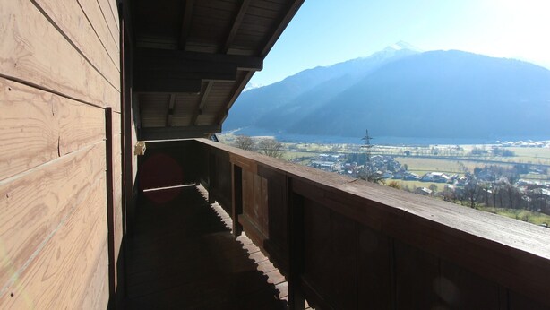 A wooden balcony with a view of a mountain and a lake. - Chalet in Austria near Ski Slopes & Nature (Mittersill)