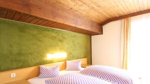 A hotel room with a wooden ceiling, a green accent wall, a bed with striped bedding, and a nightstand. - Chalet in Austria near Ski Slopes & Nature (Mittersill)