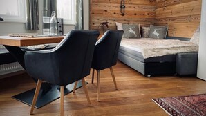 Une chambre moderne avec un mur en bois, un lit recouvert d’une couverture moelleuse, un bureau avec des chaises et une fenêtre avec des rideaux.