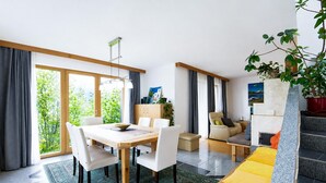 En moderne stue med spiseplads, en sofa, et sofabord og en trappe.
