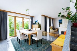 A modern living room with a dining area, a sofa, a coffee table, and a staircase.