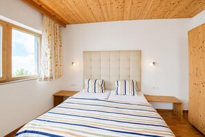 Een slaapkamer met een groot bed, twee nachtkastjes, een hoofdbord en een raam met gordijnen.
