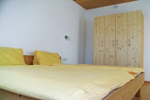 A bedroom with a wooden bed frame, a wooden wardrobe, and a single light switch on the wall. - Apartment in Aschau near Ski Lift Kaltenbach (Aschau im Zillertal)