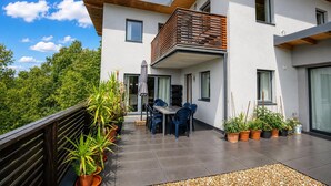 Et moderne hus med to etager, en balkon, plantekasser og udendørs møbler.