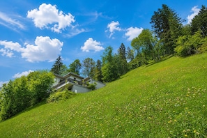 A modern house on a grassy hillside with a clear blue sky.