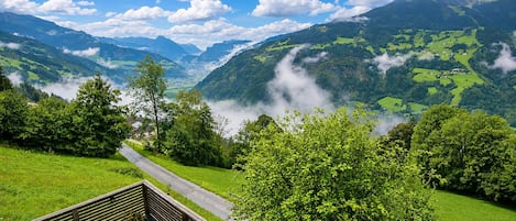 Una vista panorámica de la montaña con una carretera que atraviesa un valle, rodeado de exuberante vegetación y un cielo despejado.
