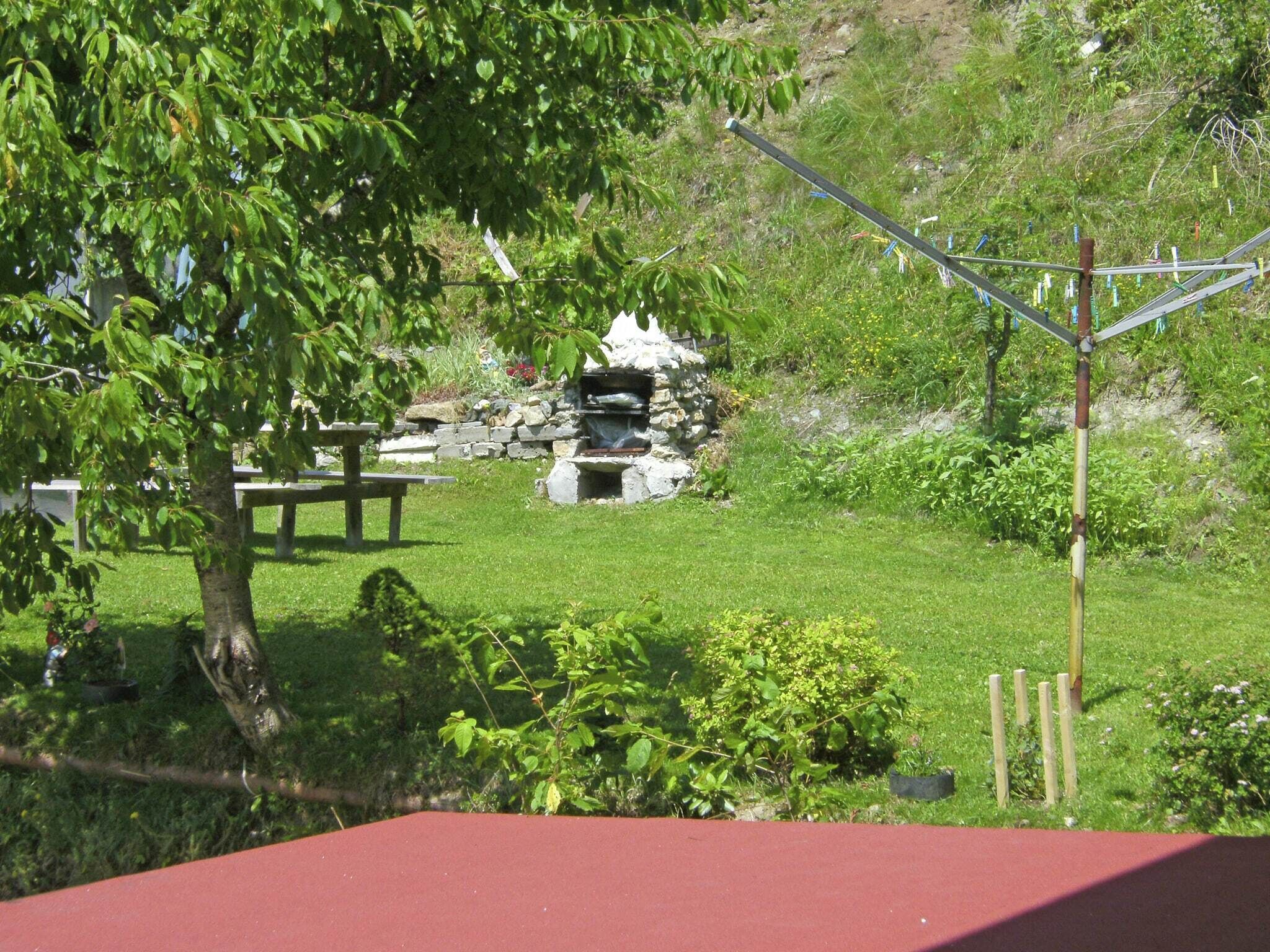 Un espace extérieur verdoyant, avec une structure en pierre, peut-être une fontaine, et une table de pique-nique.