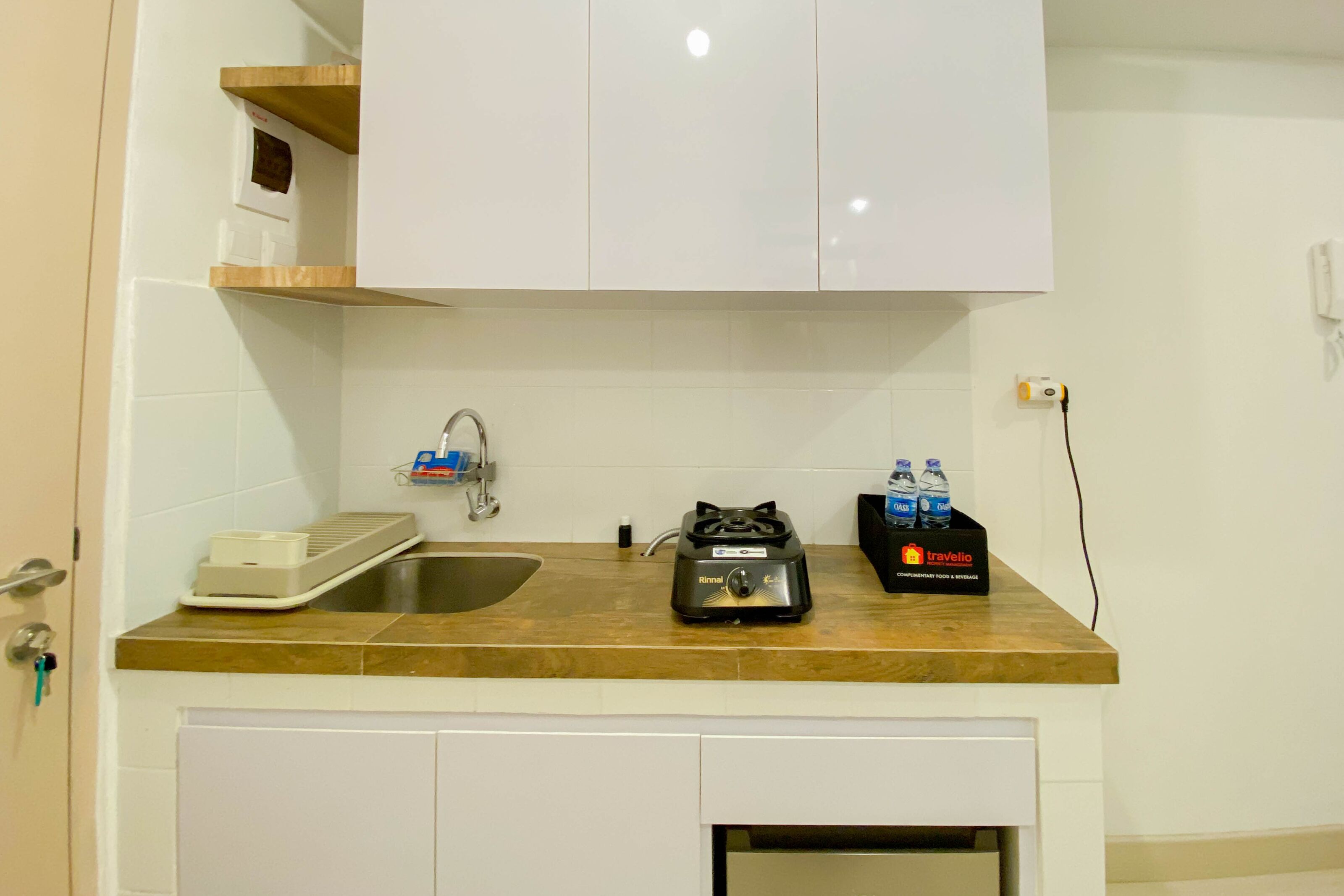 A kitchen with white cabinets, a sink, a portable gas stove, and a water dispenser.