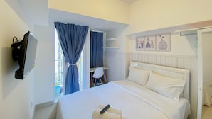A hotel room with a bed, a desk, a chair, a TV, and artwork on the wall. - Cozy And Restful Studio Tokyo Riverside Pik 2 Apartment (Teluknaga)