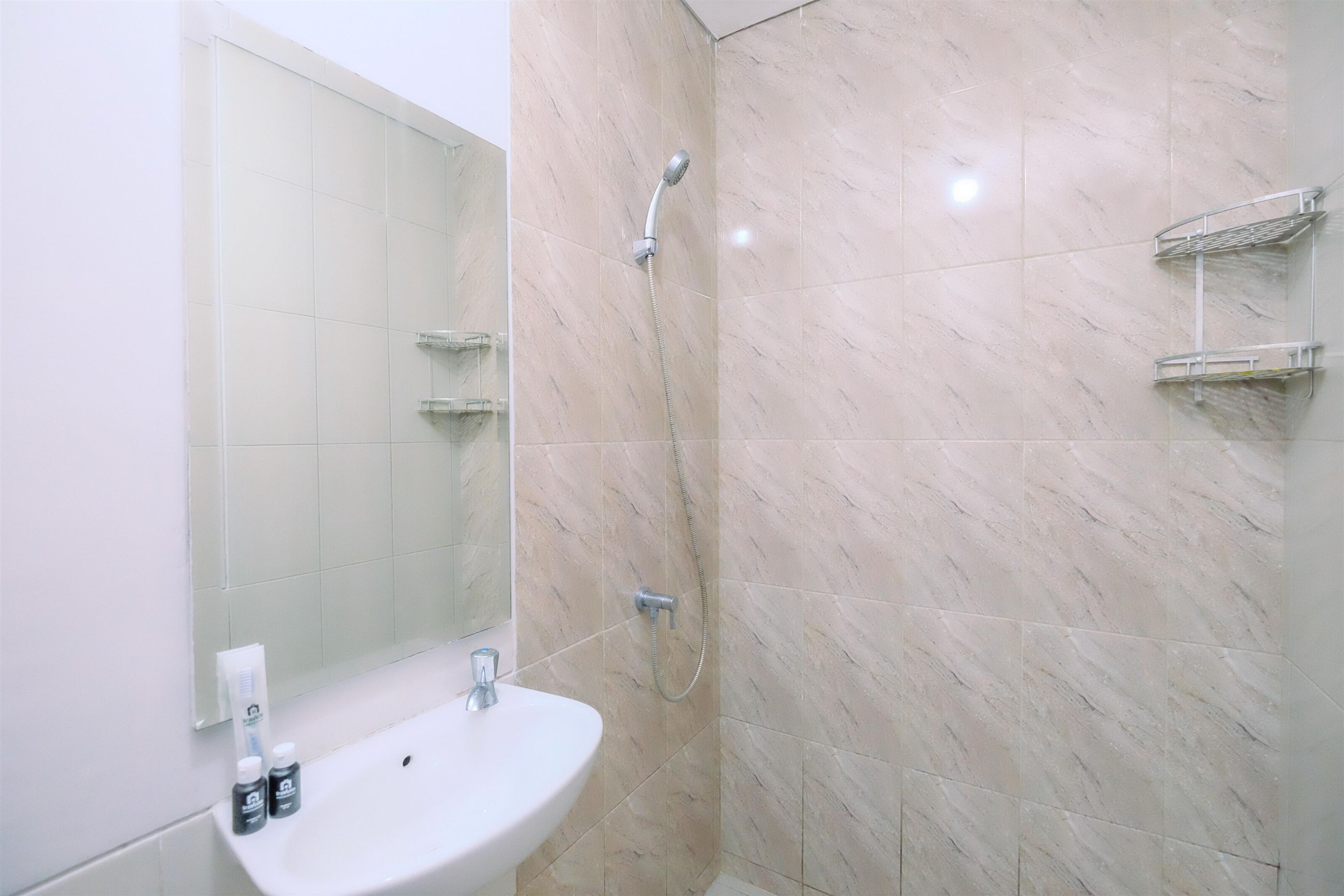 A bathroom with a sink, mirror, and shower.