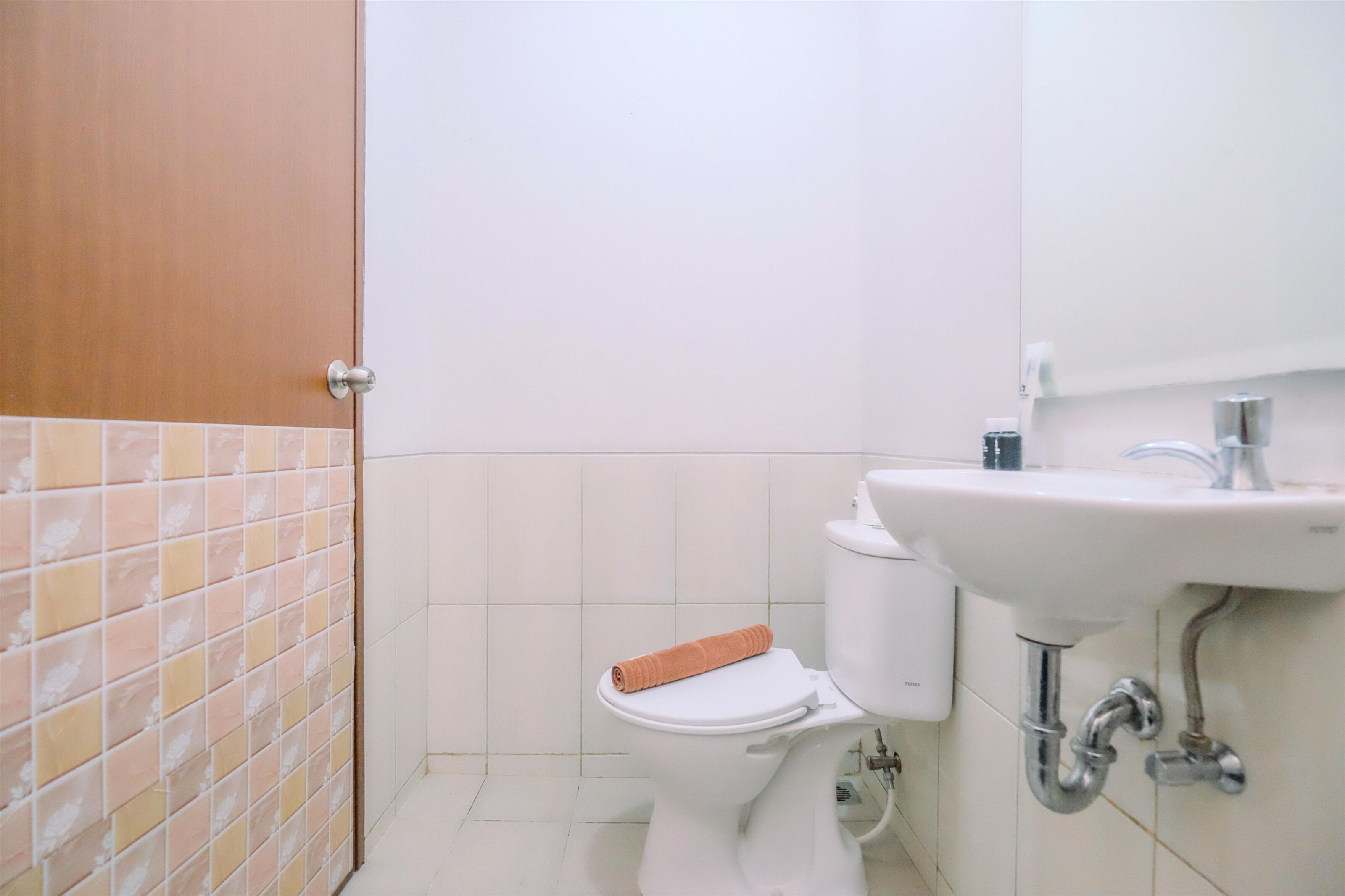 A bathroom with a toilet, sink, and tiled walls.