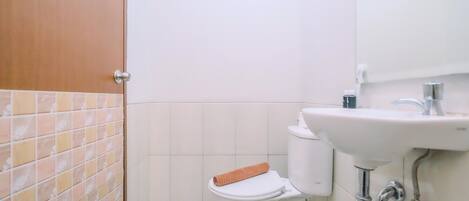 A bathroom with a toilet, sink, and tiled walls.