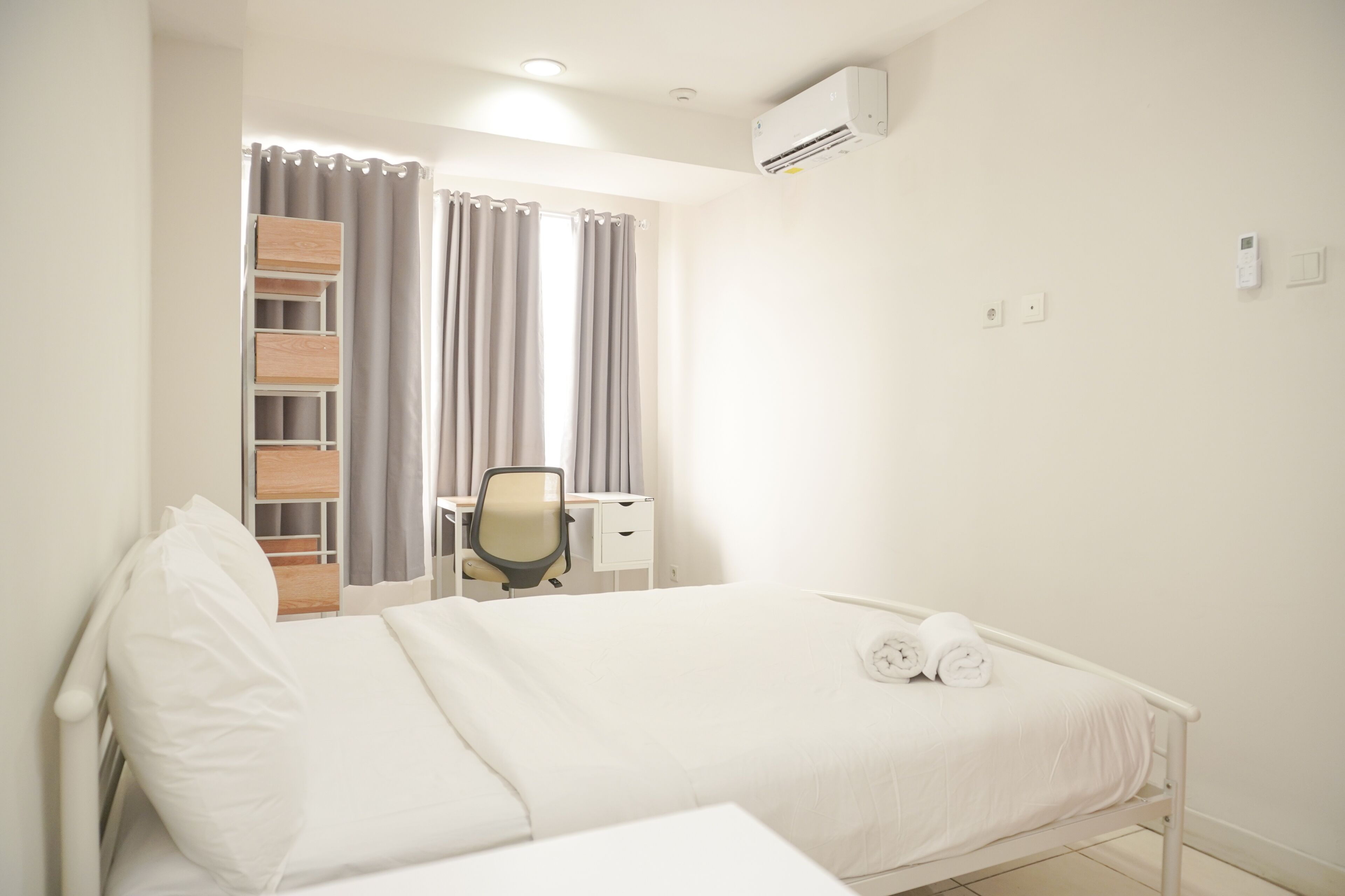 Una habitación de hotel con una cama, un escritorio y un equipo de aire acondicionado.